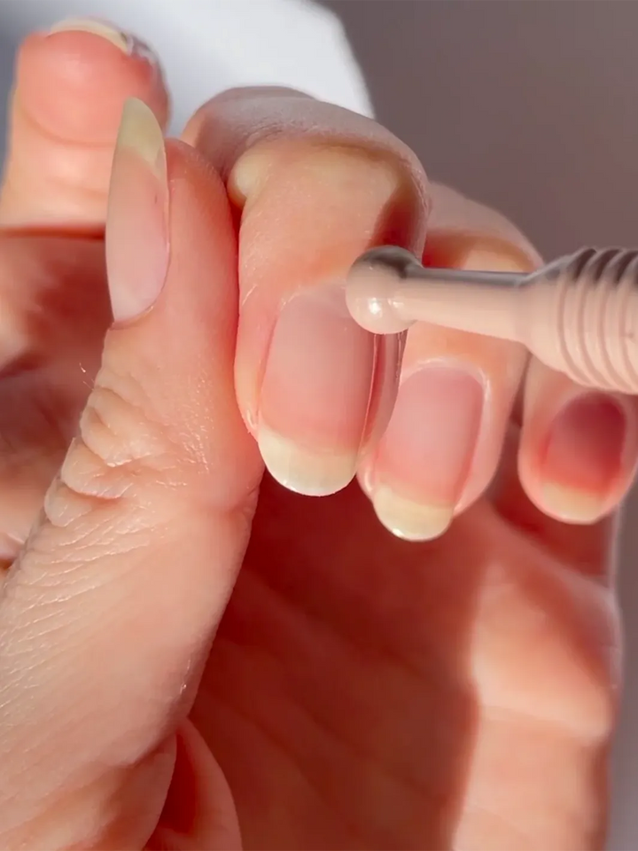 TENOVERTEN The Rose Oil cuticle treatment held in hand against a close-up beauty shot | Twentyseven Toronto