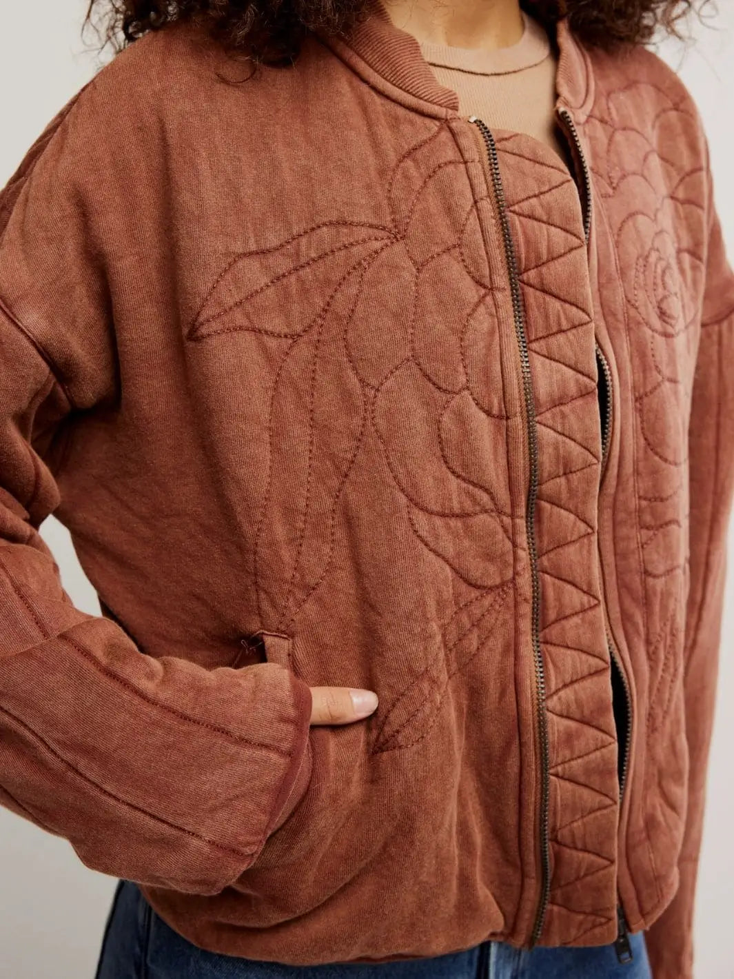 A close-up shot highlights the front slash pocket, metal zipper closure, and large embroidered floral detailing on the Free People Rose Zip-Up Sweatshirt - Cinnamon Stick | Twentyseven Toronto