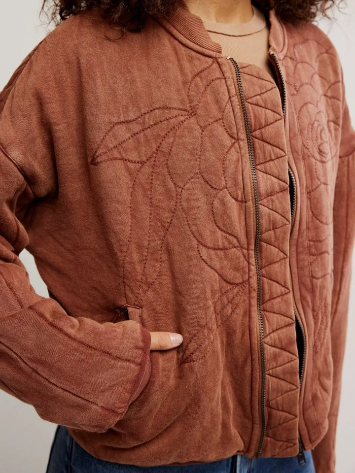 A close-up shot highlights the front slash pocket, metal zipper closure, and large embroidered floral detailing on the Free People Rose Zip-Up Sweatshirt - Cinnamon Stick | Twentyseven Toronto