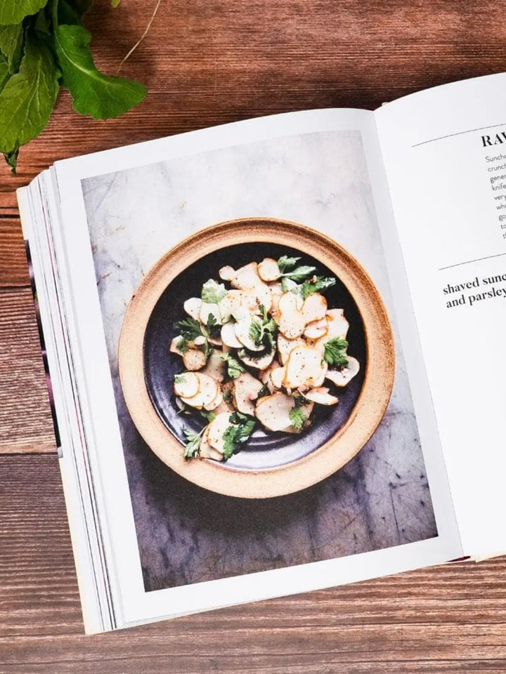 Page from Ruffage: A Practical Guide to Vegetables by by Abra Berens featuring a top-down view of a rustic ceramic bowl filled with thinly sliced sunchokes garnished with fresh parsley | Twentyseven Toronto