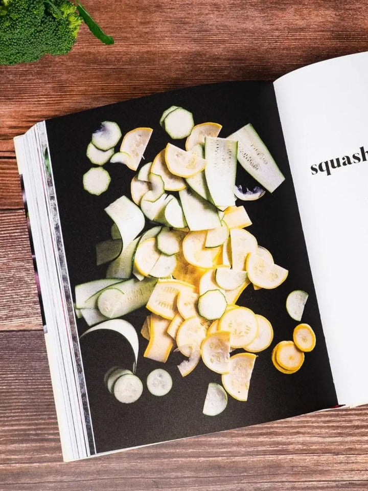 A page from Ruffage: A Practical Guide to Vegetables by by Abra Berens displaying an artistic arrangement of sliced yellow and green summer squash scattered across a solid black background | Twentyseven Toronto