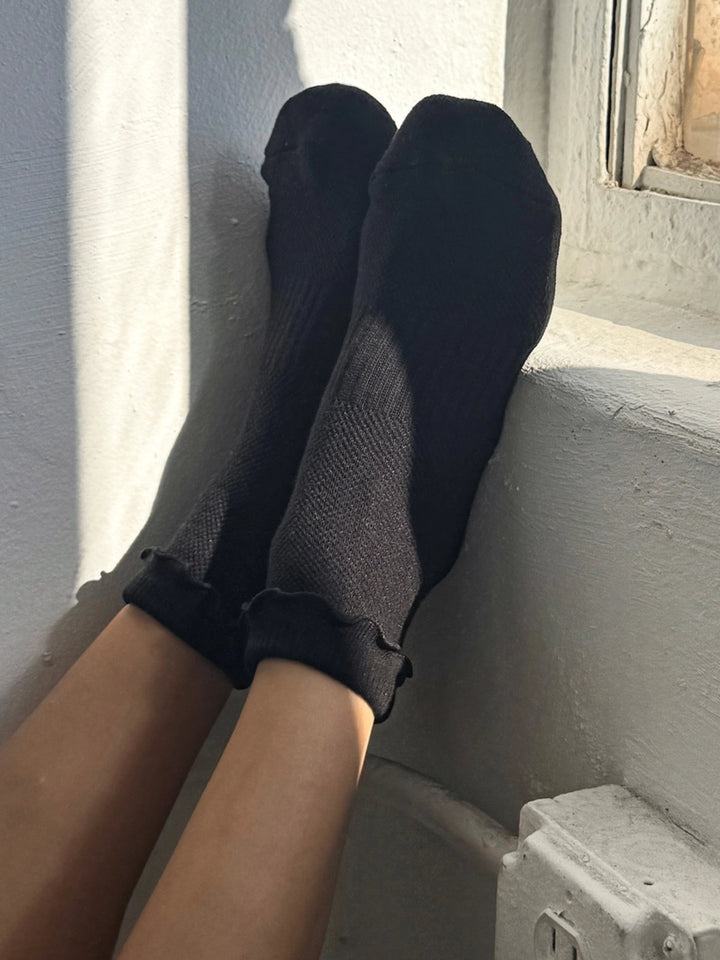 Le Bon Shoppe Ruffler Hugger Crew Socks in Black/Black with ruffled cuffs, worn in natural light | Twentyseven Toronto