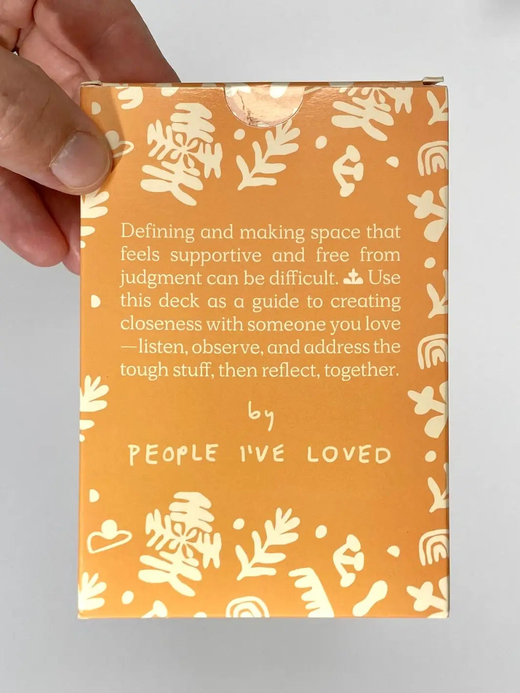 The back of the outer box for the A Safe Space For Us Deck from People I've Loved features a supportive description of the deck's purpose and a patterned orange border | Twentyseven Toronto