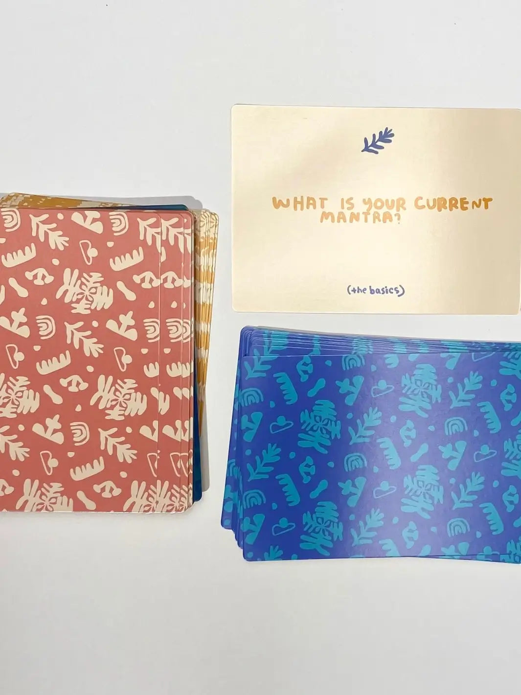 A prompt card asking "What is your current mantra?" is showcased face up next to two piles of cards from the A Safe Space For Us Deck from People I've Loved | Twentyseven Toronto