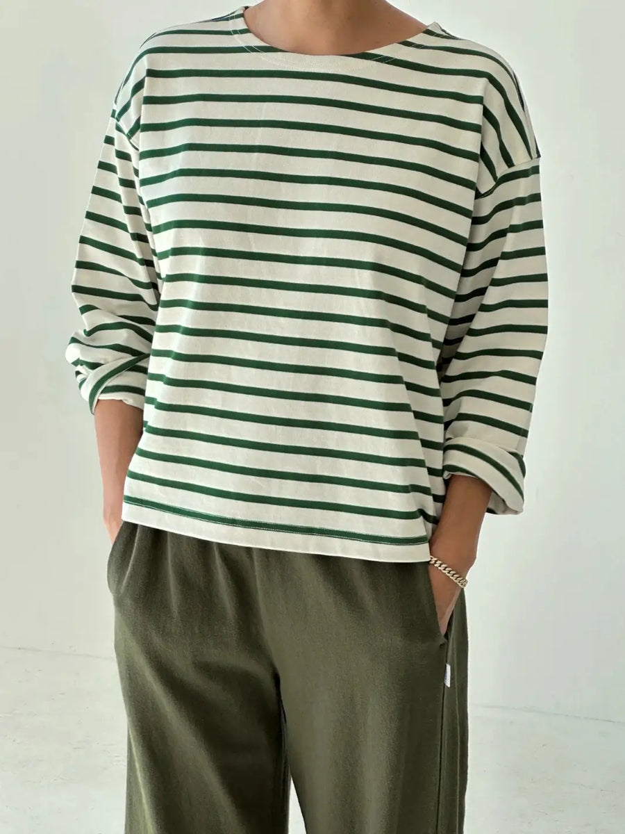 Person wearing a green and white striped 'Sailor Top' long sleeve shirt in 'Pine Stripe' with green pants from Le Bon Shoppe on a white background | Twentyseven Toronto