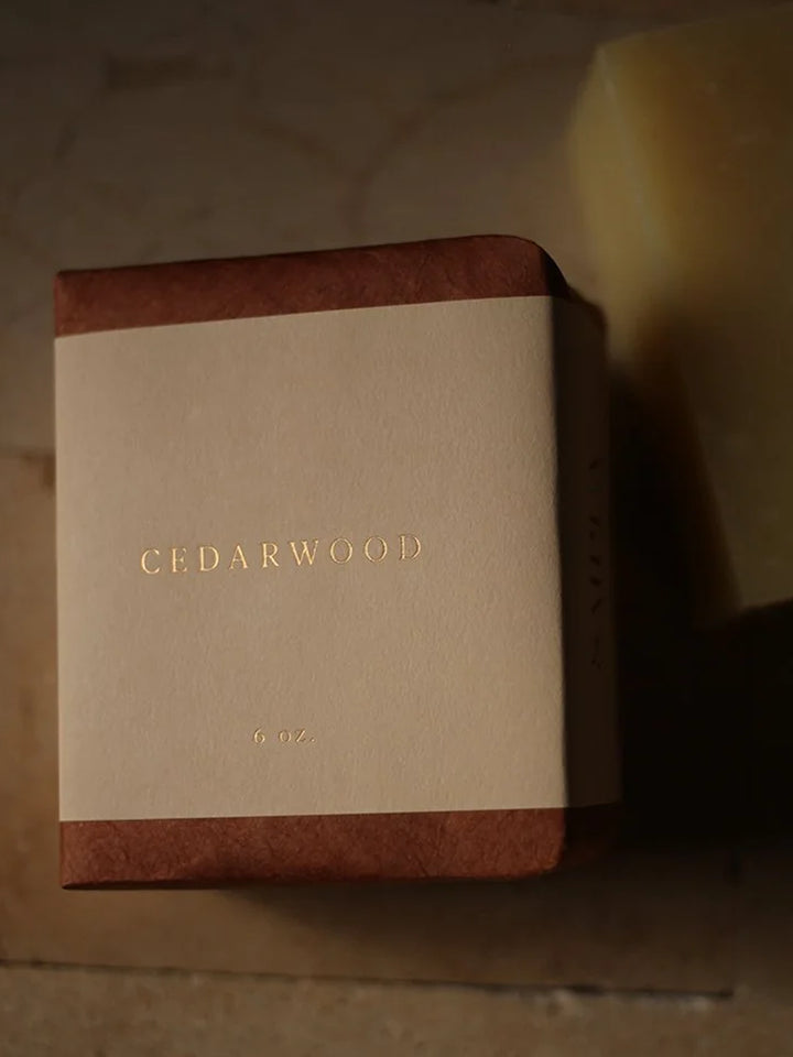 Cedarwood Bar Soap with cream paper wrap in warm, low lighting, highlighting its rich brown colour and minimalist packaging | Twentyseven Toronto