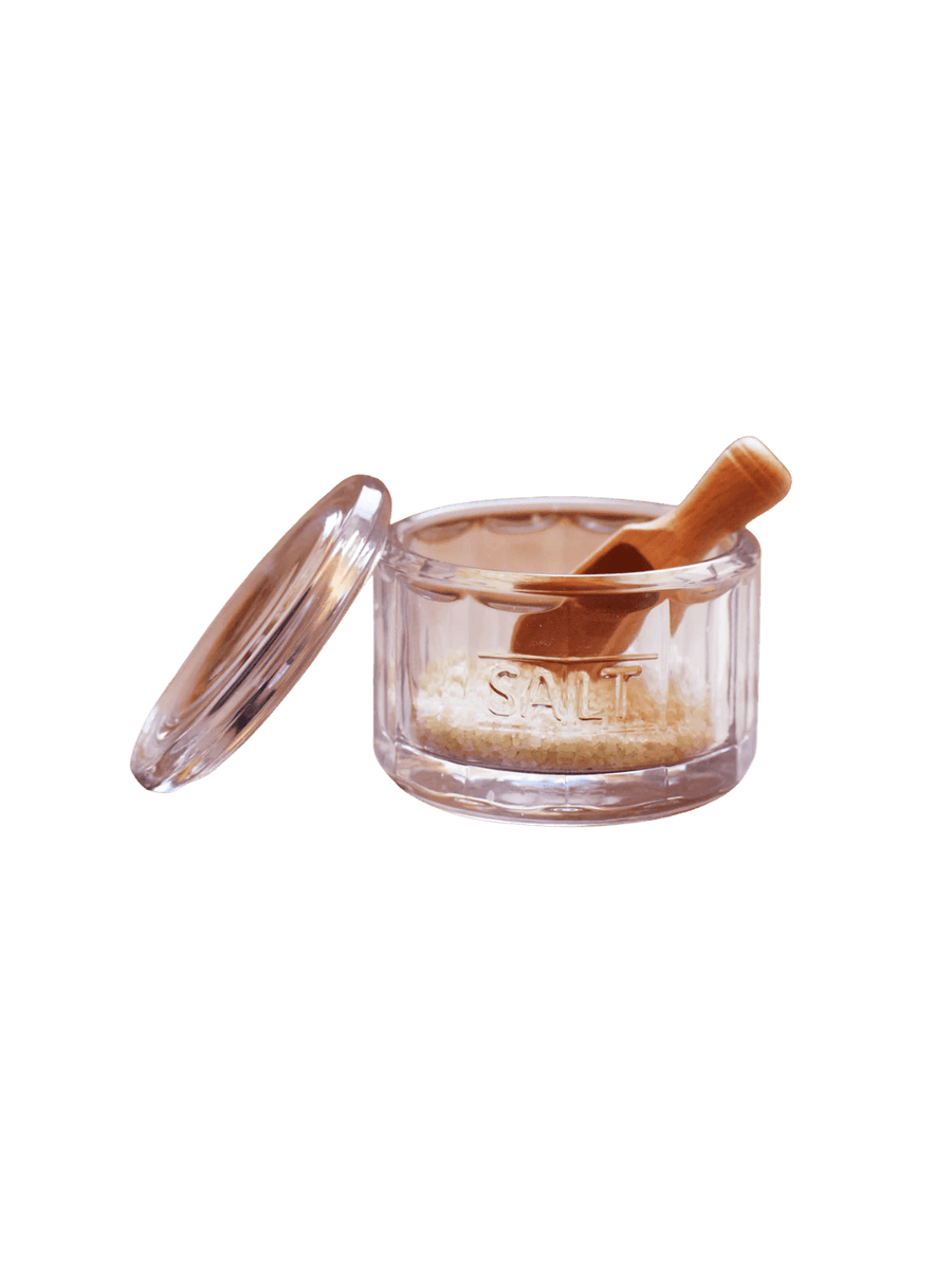 A ribbed glass Salt Pot w/ Scoop from Earth and Nest with the word "SALT" embossed on the front, complete with an open glass lid and an included wooden scoop | Twentyseven Toronto