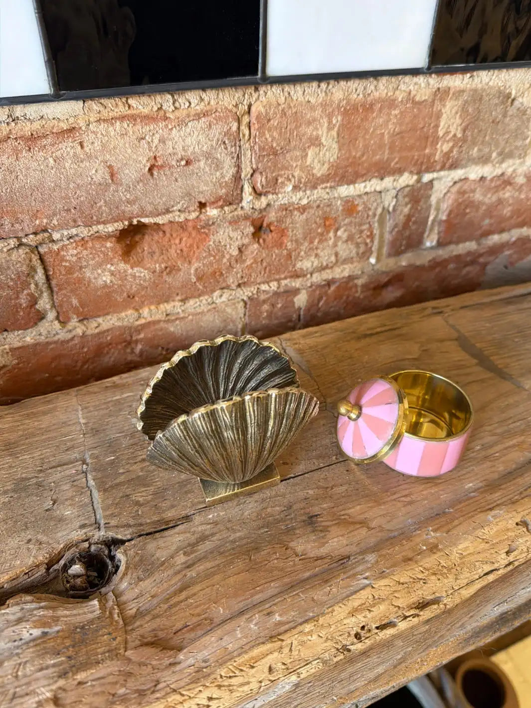 Decorative gold shell shaped holder and pink and gold box by Doing Goods on a wooden surface with a brick wall background | Twentyseven Toronto