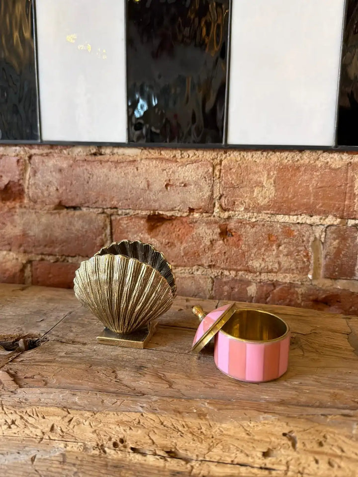 Decorative gold shell shaped holder and pink and gold box by Doing Goods on a wooden surface with a brick wall background | Twentyseven Toronto
