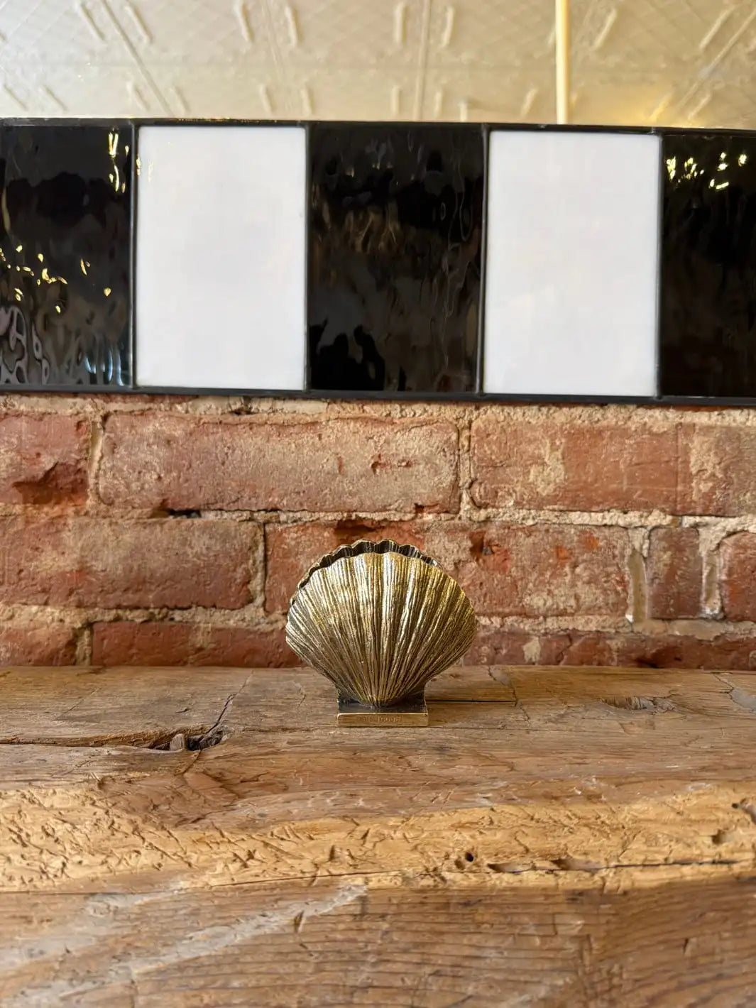 Decorative gold shell shaped holder and pink and gold box by Doing Goods on a wooden surface with a brick wall background | Twentyseven Toronto