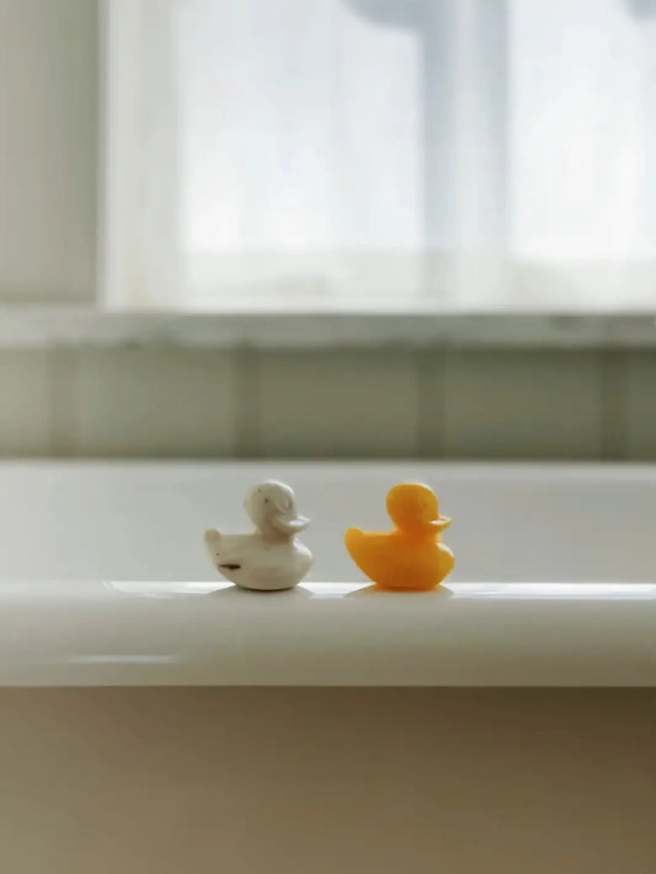 Two Sheep's Milk Soap in 'Duckling' from Burstenhaus Redecker, one white and one yellow on a bathtub | Twentyseven Toronto