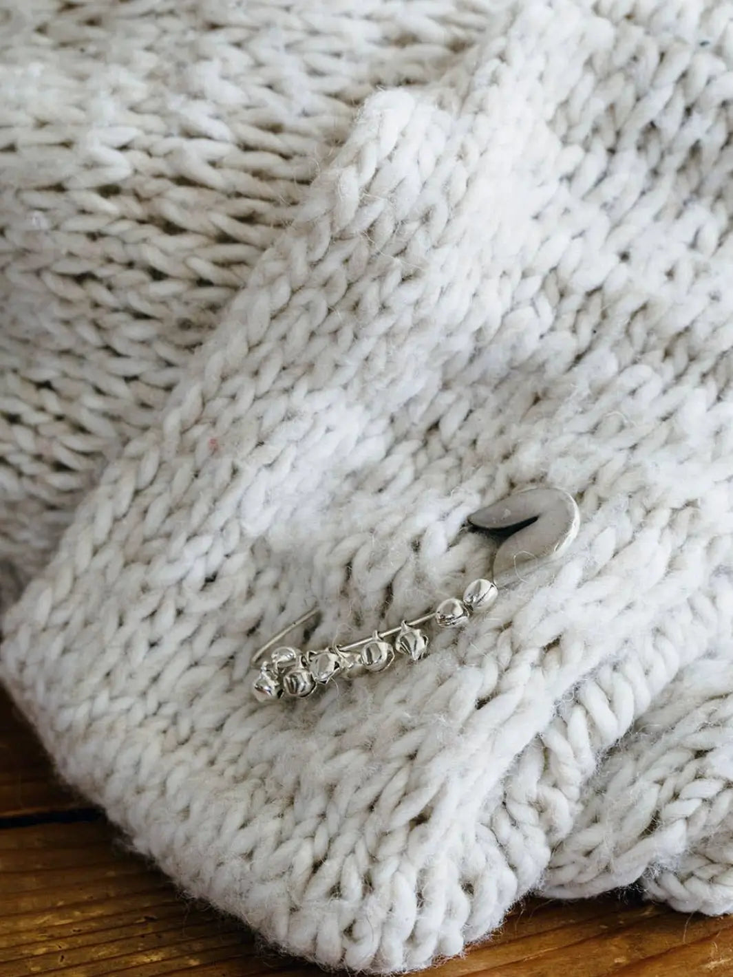 Fog Linen Work Silver Safety Pin Bell Small  pinned to a chunky white knit sweater | Twentyseven Toronto