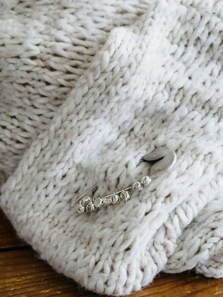 Fog Linen Work Silver Safety Pin Bell Small  pinned to a chunky white knit sweater | Twentyseven Toronto