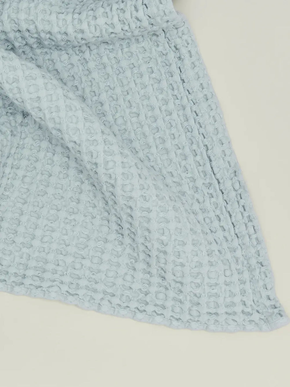 A close-up view highlights the intricate woven grid texture of a pale blue towel from the Simple Waffle Towel - Sky from Hawkins New York collection | Twentseven Toronto
