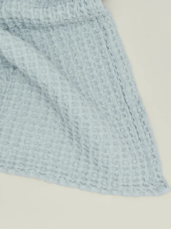 A close-up view highlights the intricate woven grid texture of a pale blue towel from the Simple Waffle Towel - Sky from Hawkins New York collection | Twentseven Toronto
