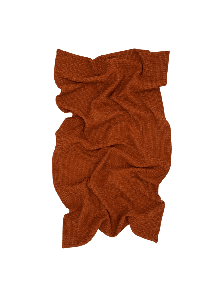 A warm, rust-colored bath sheet crumpled to highlight the unique weave of the Simple Waffle Towel - Terracotta from Hawkins New York | Twentyseven Toronto
