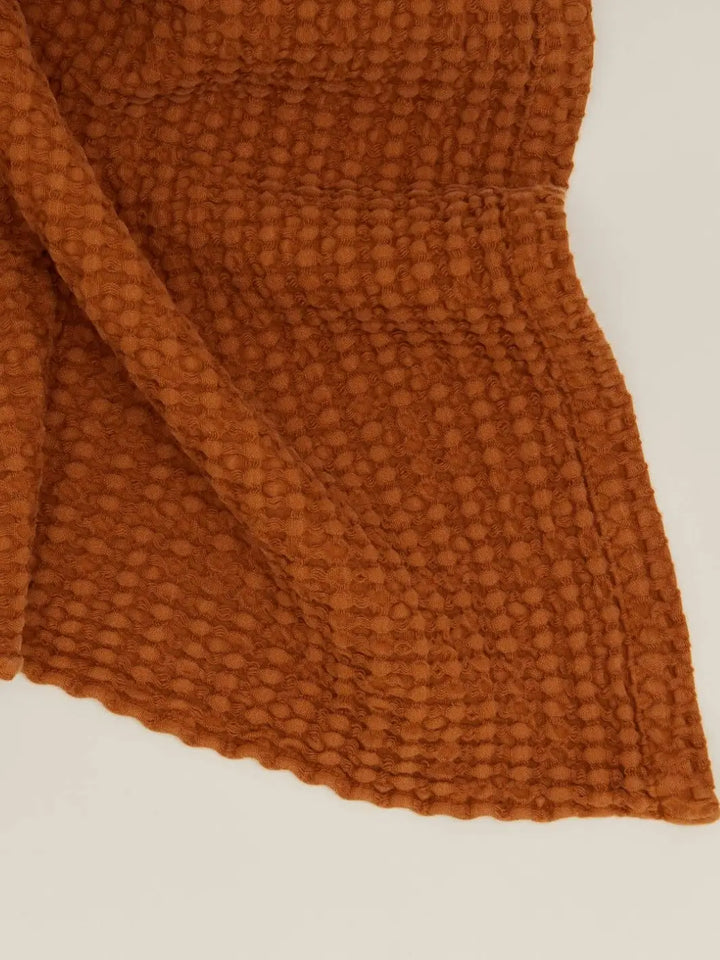 A tight close-up showcases the deep, grid-like woven texture and soft hemline of the Simple Waffle Towel - Terracotta from Hawkins New York | Twentyseven Toronto