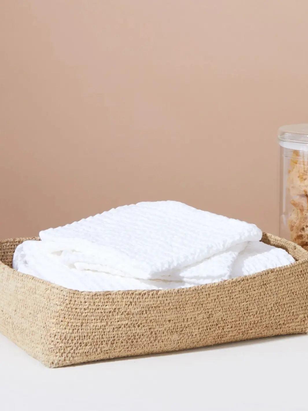 Folded waffle towels neatly tucked inside a woven jute storage basket from Hawkins New York | Twentyseven Toronto