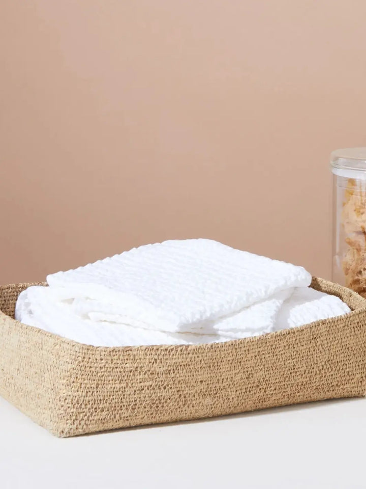 Folded waffle towels neatly tucked inside a woven jute storage basket from Hawkins New York | Twentyseven Toronto