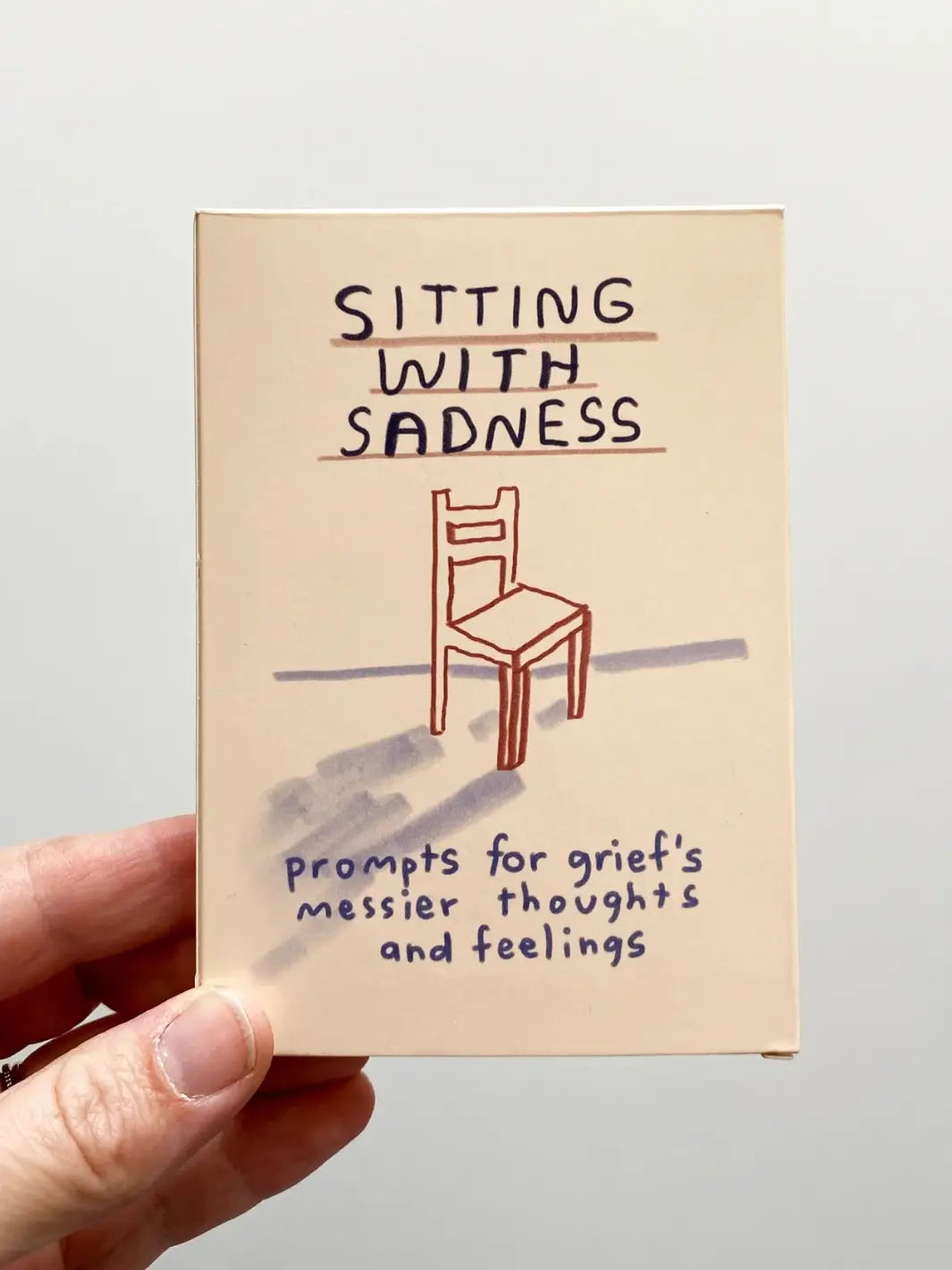 The front of the Sitting With Sadness Deck from People I've Loved is displayed, featuring a simple line drawing of a chair and the subtitle "prompts for grief's messier thoughts and feelings" | Twentyseven Toronto