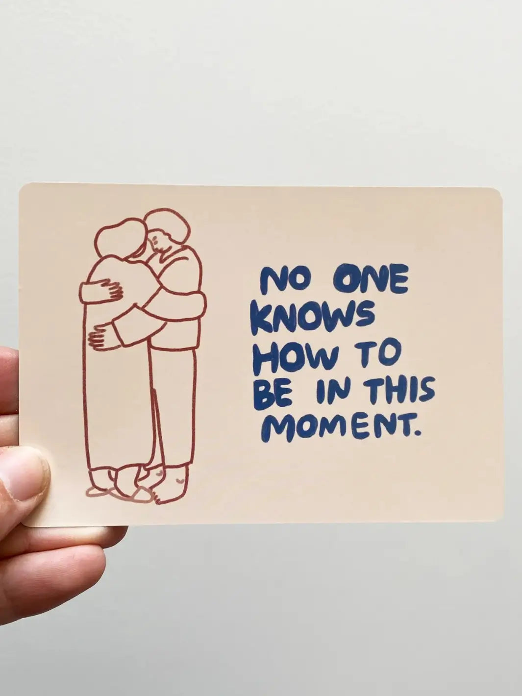 An illustrated card from the Sitting With Sadness Deck from People I've Loved shows two figures embracing next to the hand-lettered text, "No one knows how to be in this moment" | Twentyseven Toronto