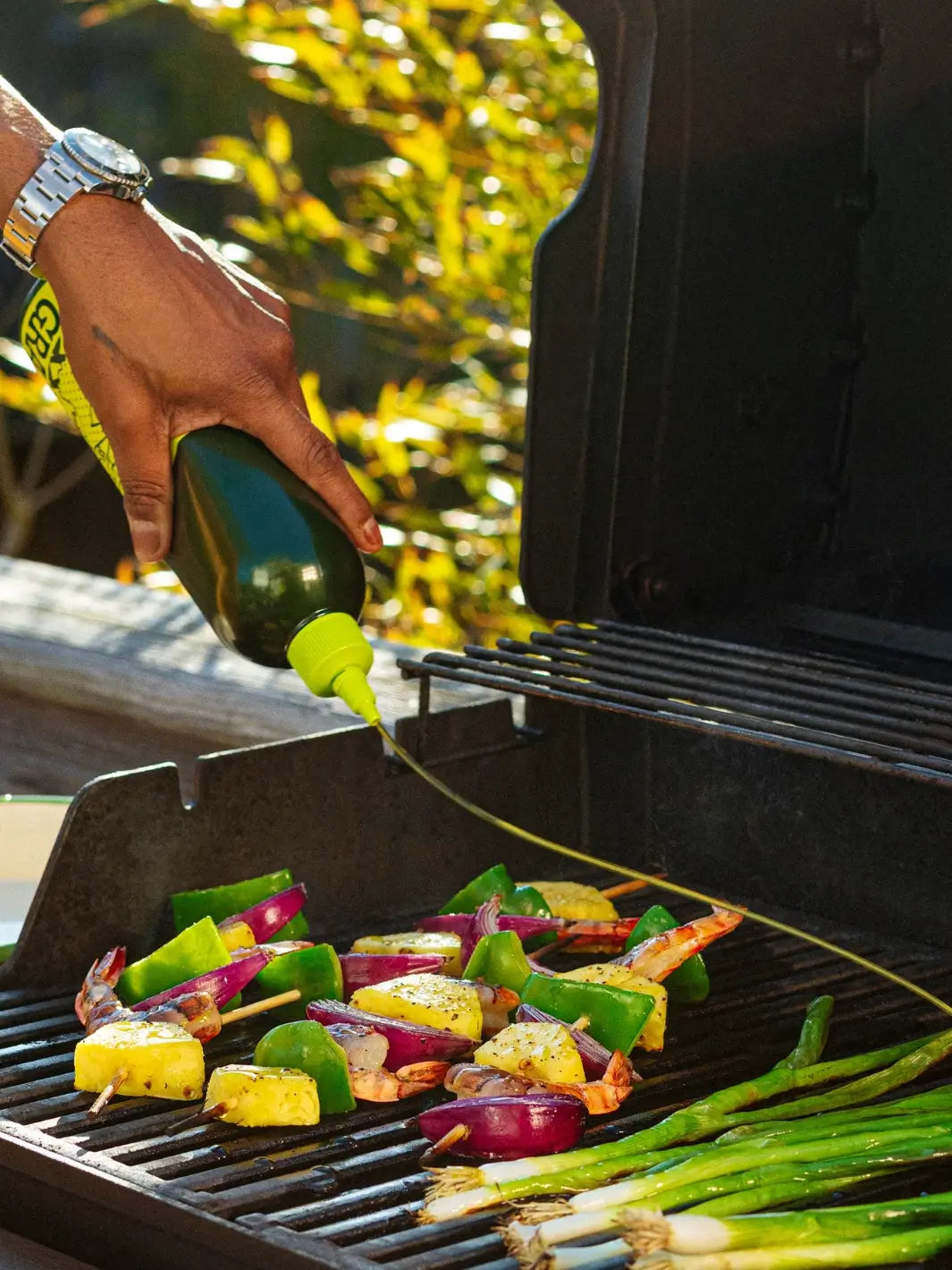 Person grilling vegetables on a barbecue grill outdoors using Graza 'Sizzle' extra virgin olive oil | Twentyseven Toronto