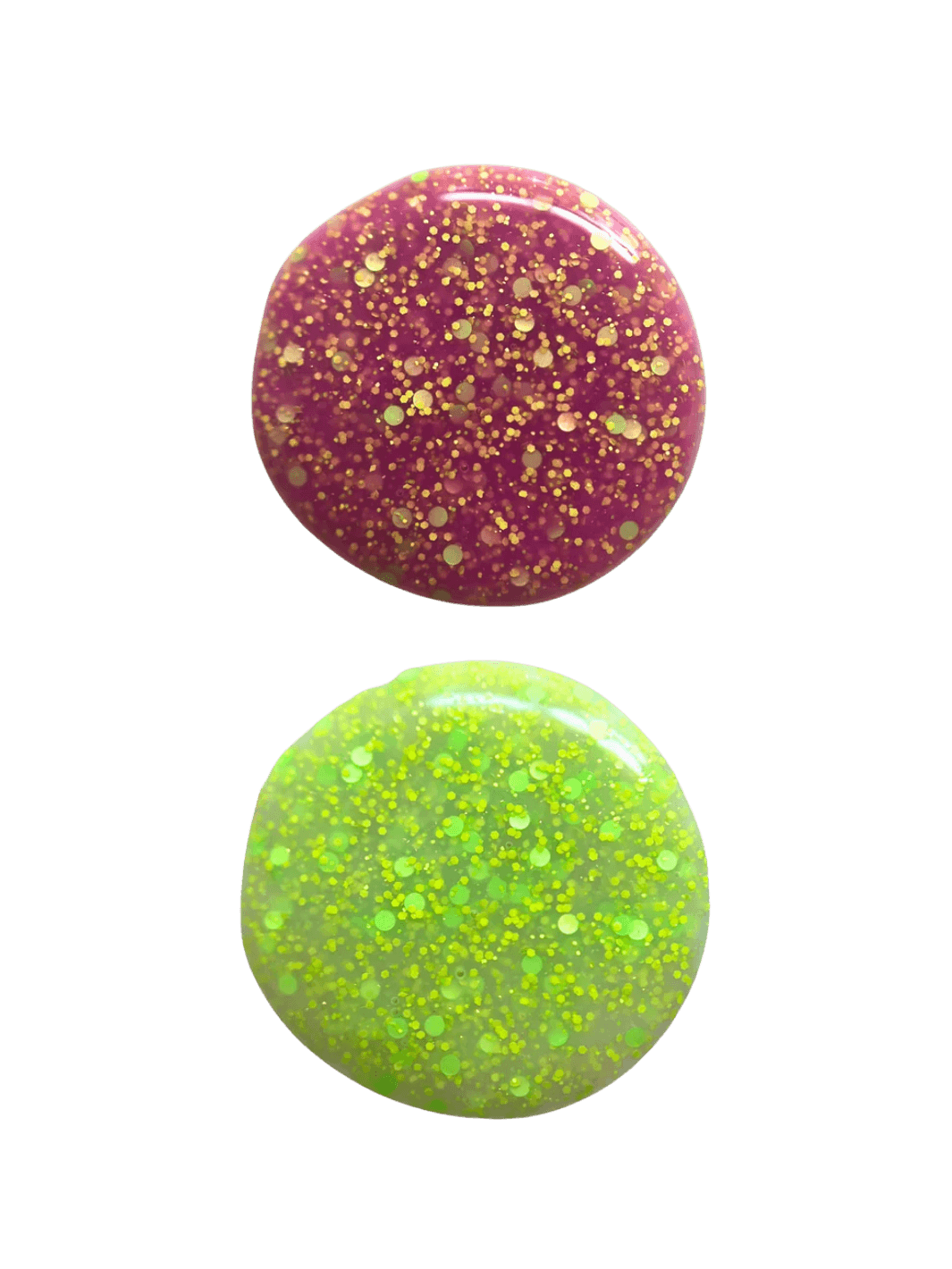 Two circular swatches of glittery 'Skunk Dreams' nail polish by Death Valley Nails, one pink and one green, on a transparent background | Twentyseven Toronto