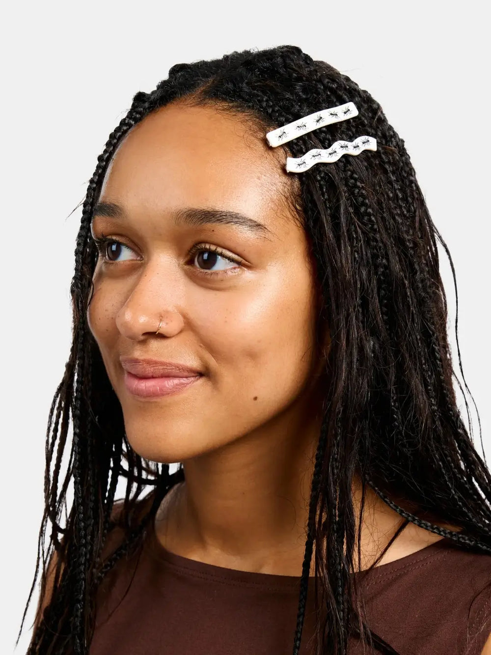 A model with long dark braids styles her hair with two white hair barrettes from the CHUNKS Slides in Ants Barrette set | Twentyseven Toronto