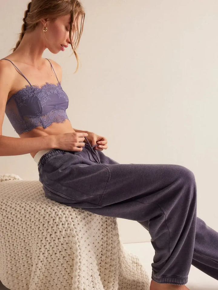 A side profile view shows a model sitting and adjusting the drawstring waistband of the relaxed, faded fleece Free People Slow It Down Joggers in Peacoat | Twentyseven Toronto