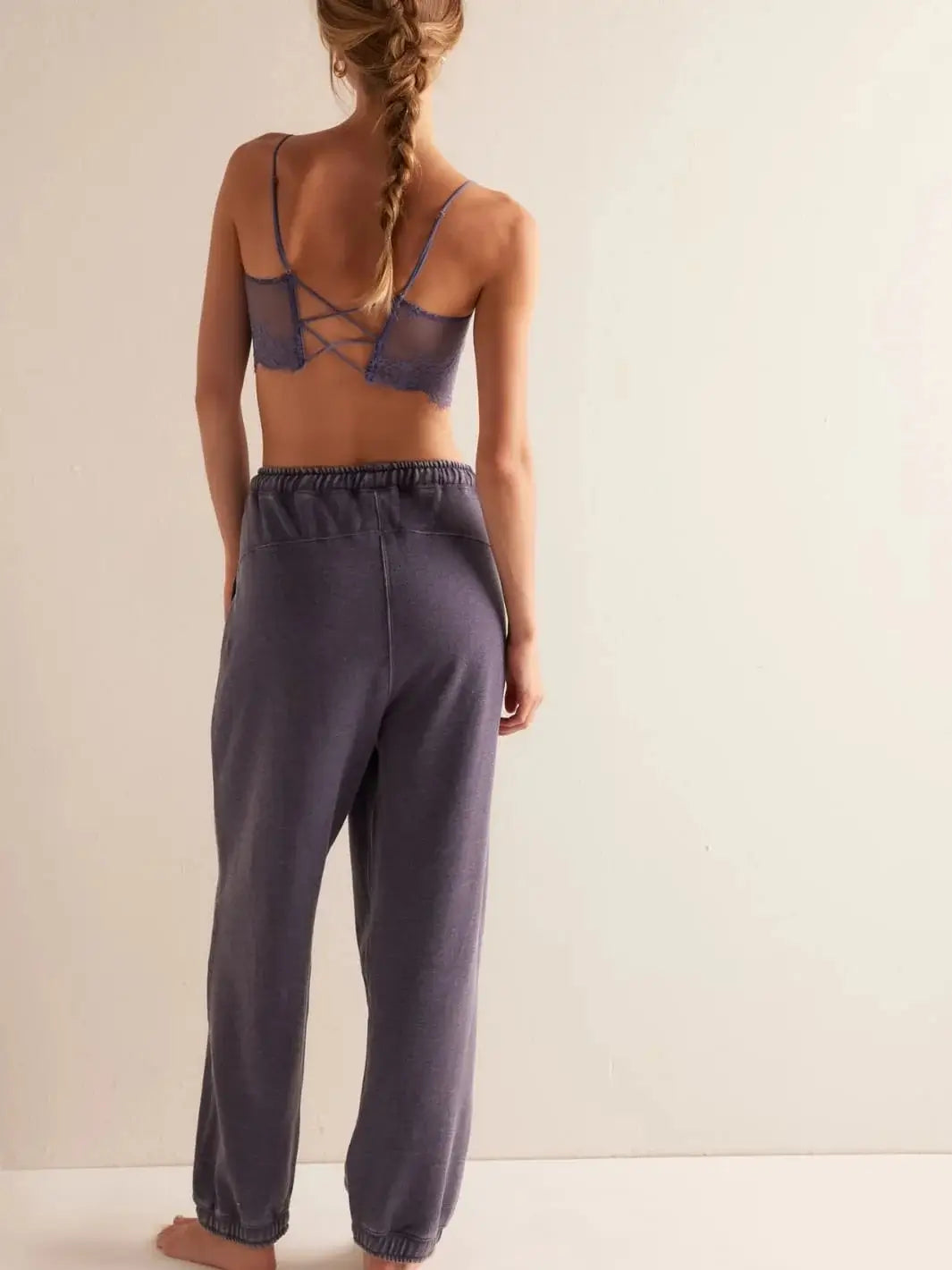 A direct rear view highlights the gathered elastic waistband, loose fit, and tapered ankles of the Free People Slow It Down Joggers in Peacoat paired with a matching lace bralette | Twentyseven Toronto