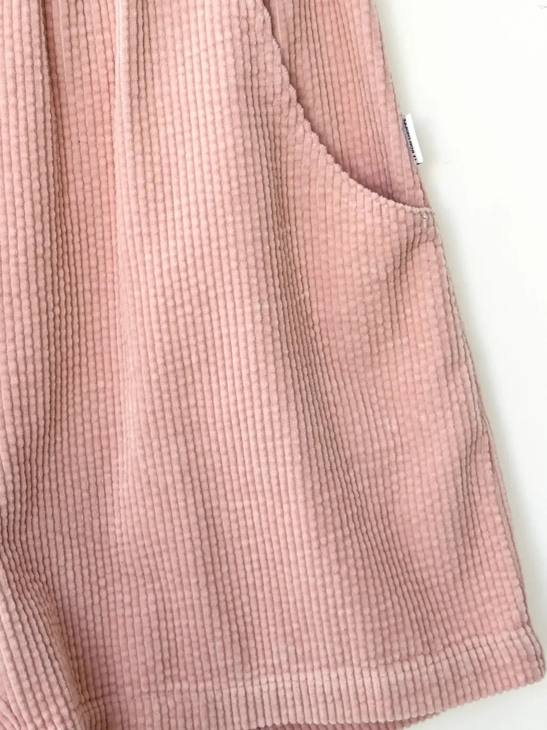 Close-up of a pink 'Soft Corduroy City Shortts' fabric in 'Baby Pink' with a pocket from Le Bon Shoppe on a white background | Twentyseven Toronto