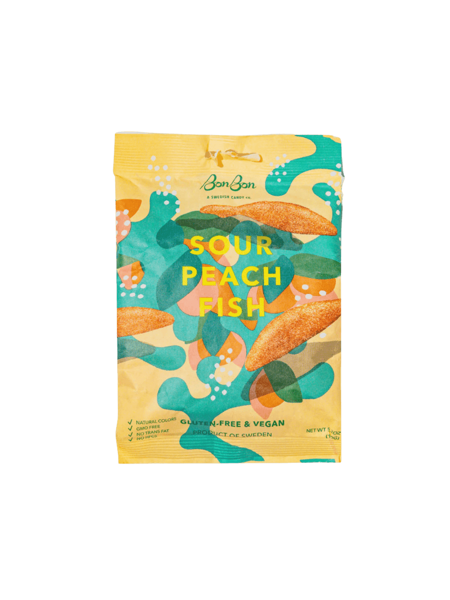 A sealed yellow pouch featuring abstract green, teal, and peach graphics displays the front packaging of Sour Peach Fish Swedish Candy from BonBon NYC against a transparent background | Twentyseven Toronto