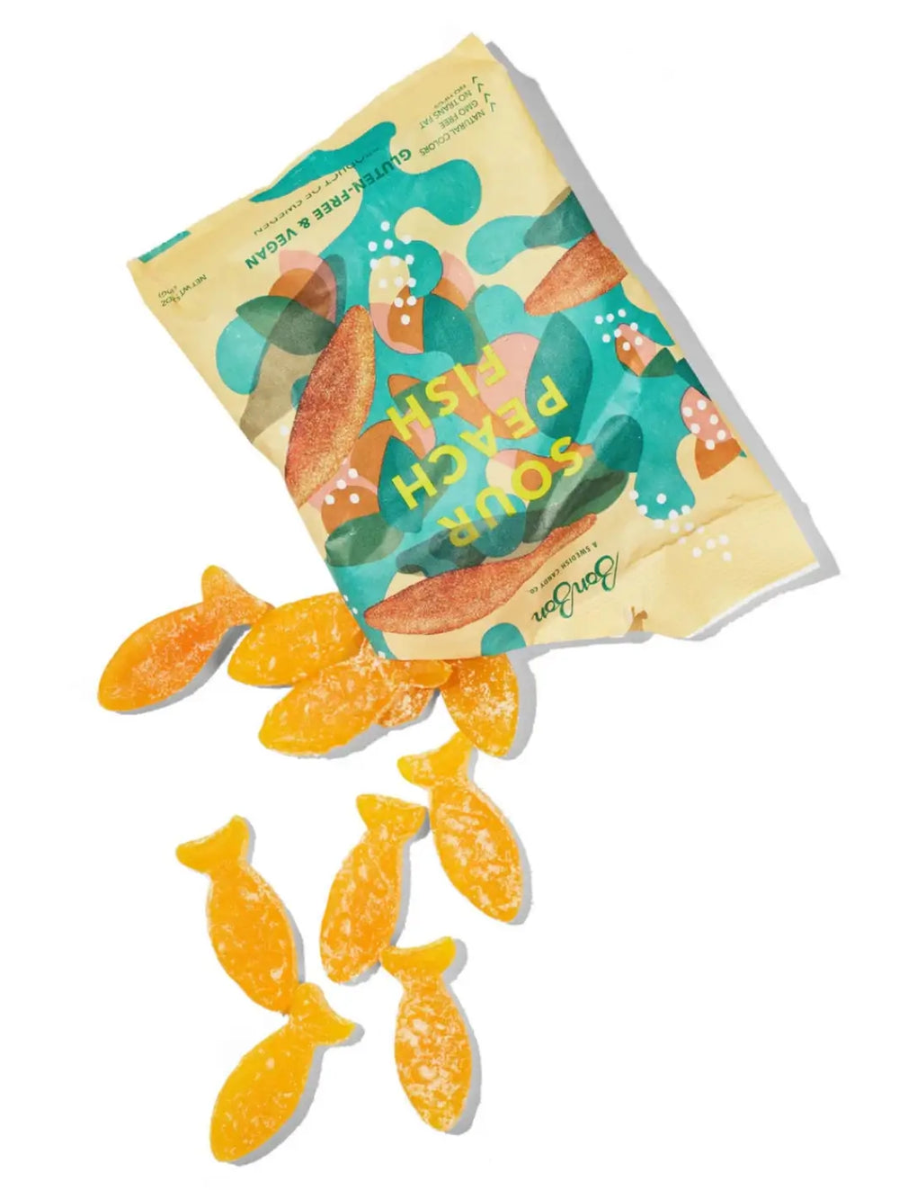 Several orange, sugar-coated fish-shaped gummy candies spill out from an open bag of Sour Peach Fish Swedish Candy from BonBon NYC onto a clean white surface | Twentyseven Toronto