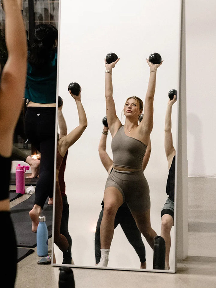 Group fitness class exercising with black Halfmoon Sphere Weights | Twentyseven Toronto