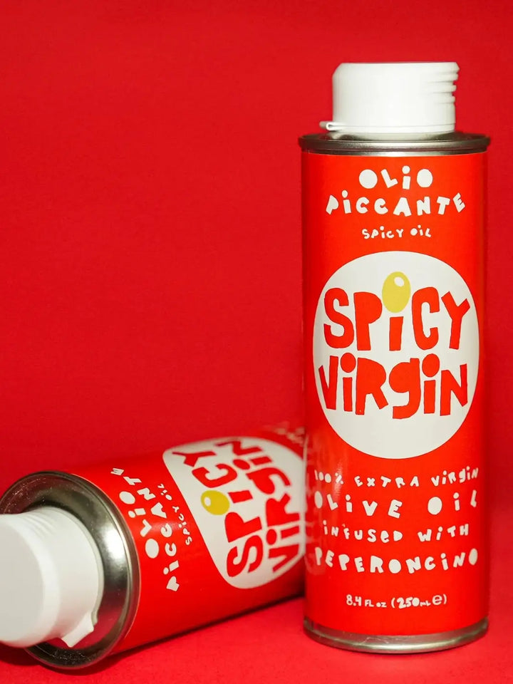 Two red cans of 'Spicy Virgin' olive oil from Casa Virgin on a red background | Twentyseven Toronto