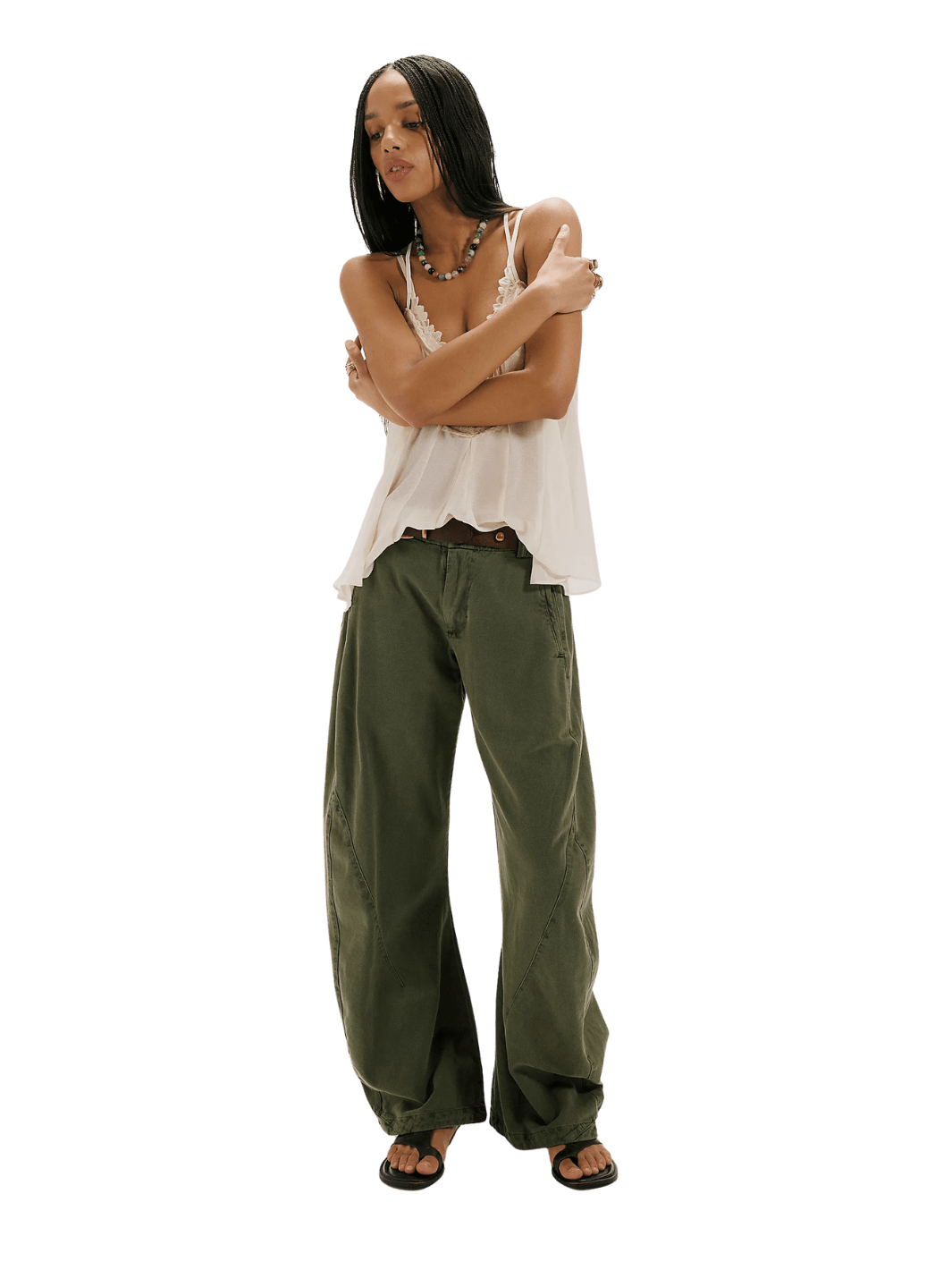 A model wearing the dark green wide-leg Free People Spotlight Washed Barrel Chino Trousers in Dusty Olive, a lace-trimmed tank top, and black sandals | Twentyseven Toronto
