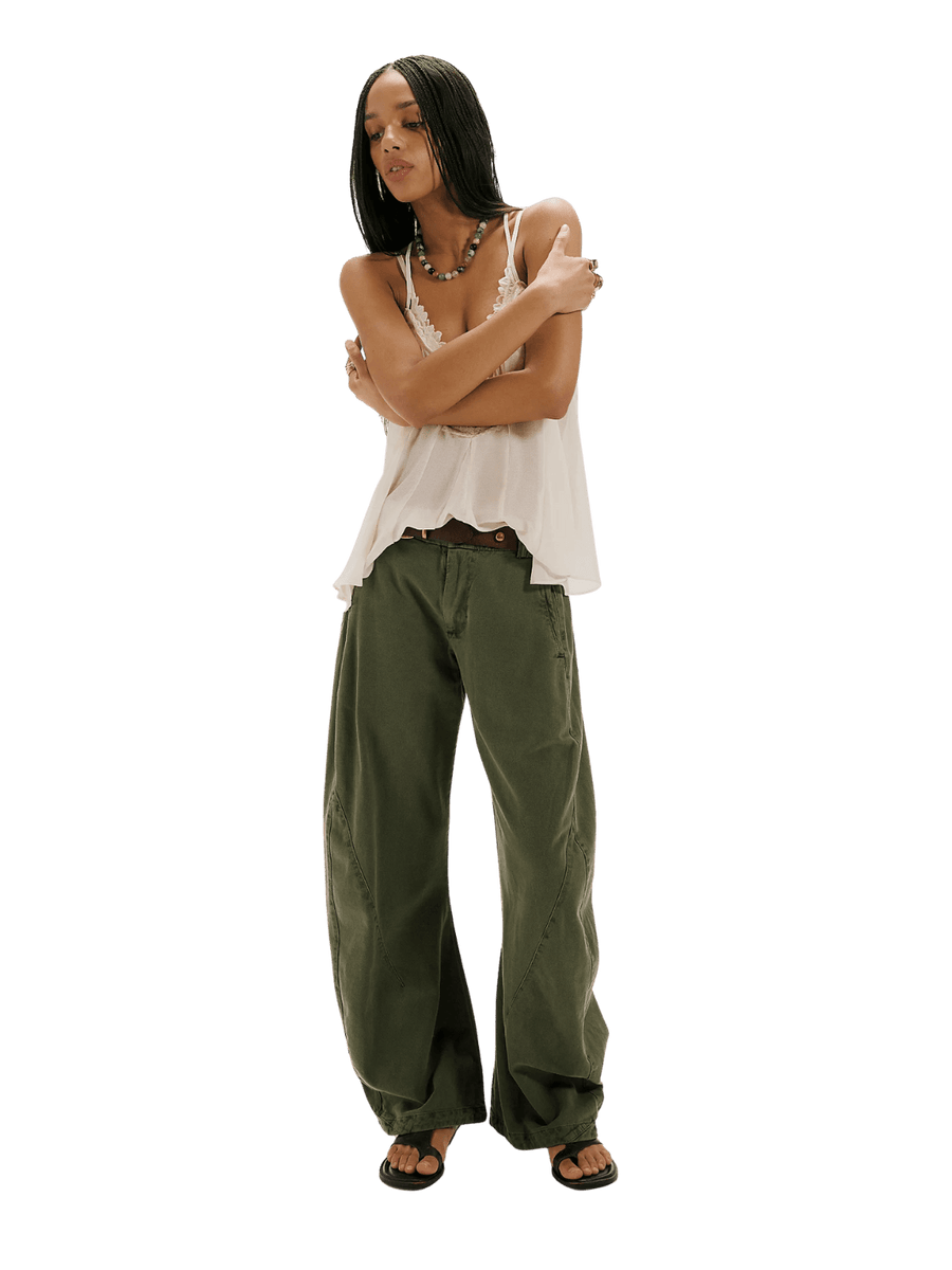 A model wearing the dark green wide-leg Free People Spotlight Washed Barrel Chino Trousers in Dusty Olive, a lace-trimmed tank top, and black sandals | Twentyseven Toronto