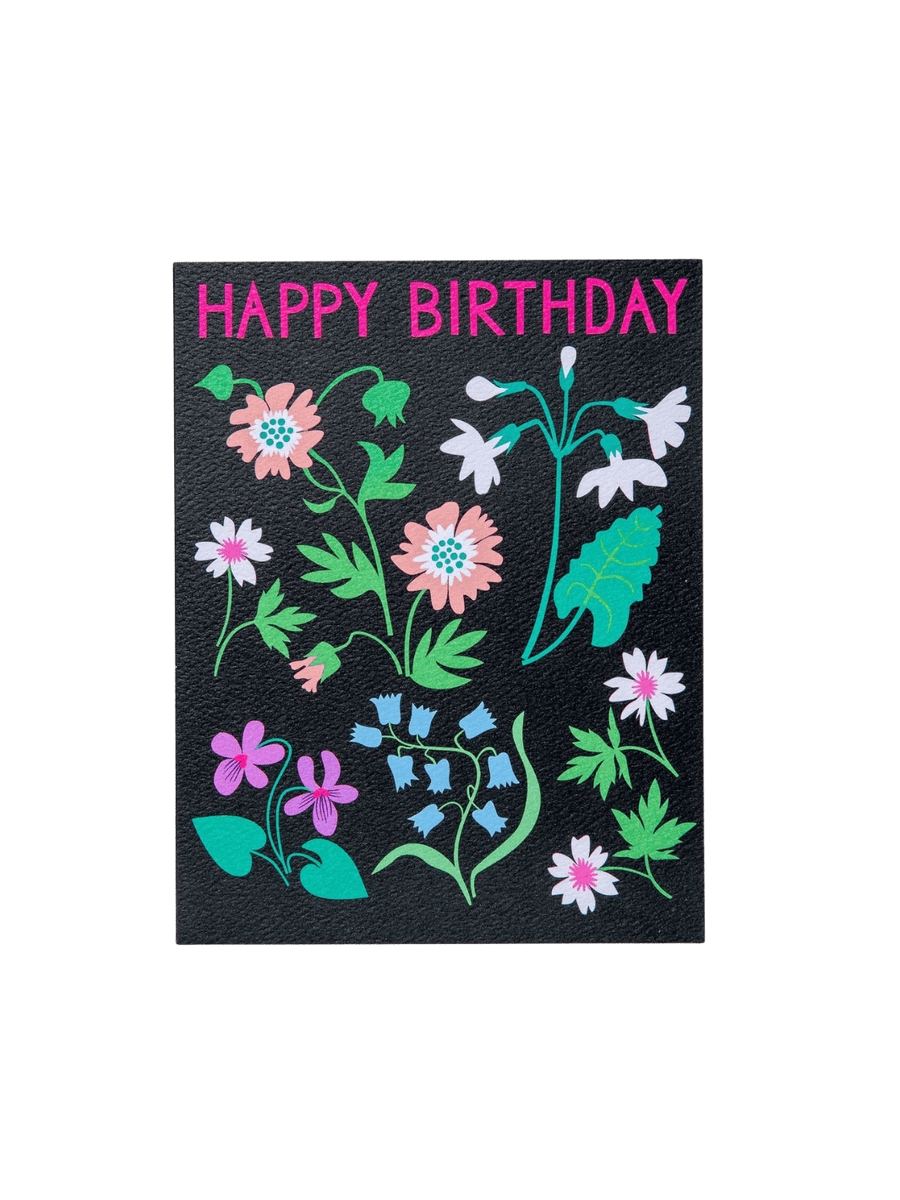 The front of the Banquet Workshop Spring Meadow Happy Birthday Note Card features the words "HAPPY BIRTHDAY" in bright neon pink above a colourful illustration of scattered wildflowers on a textured black background | Twentyseven