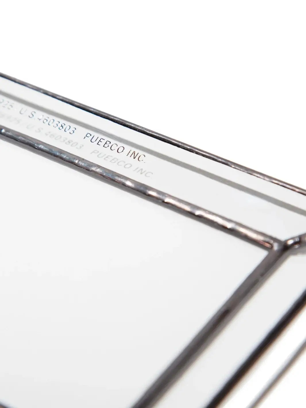 A close-up, detailed view of the corner of a Stained Glass Tray from Puebco, highlighting the dark soldered edges and the clean, stamped brand text along the inner rim | Twentyseven Toronto