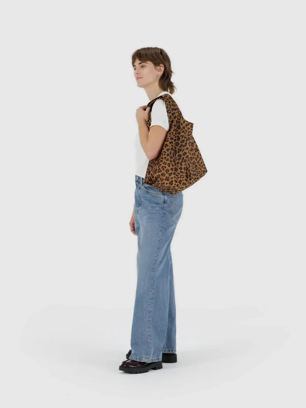 A lifestyle shot shows a person carrying the BAGGU Standard Baggu in Leopard over their shoulder against a white background | Twentyseven Toronto