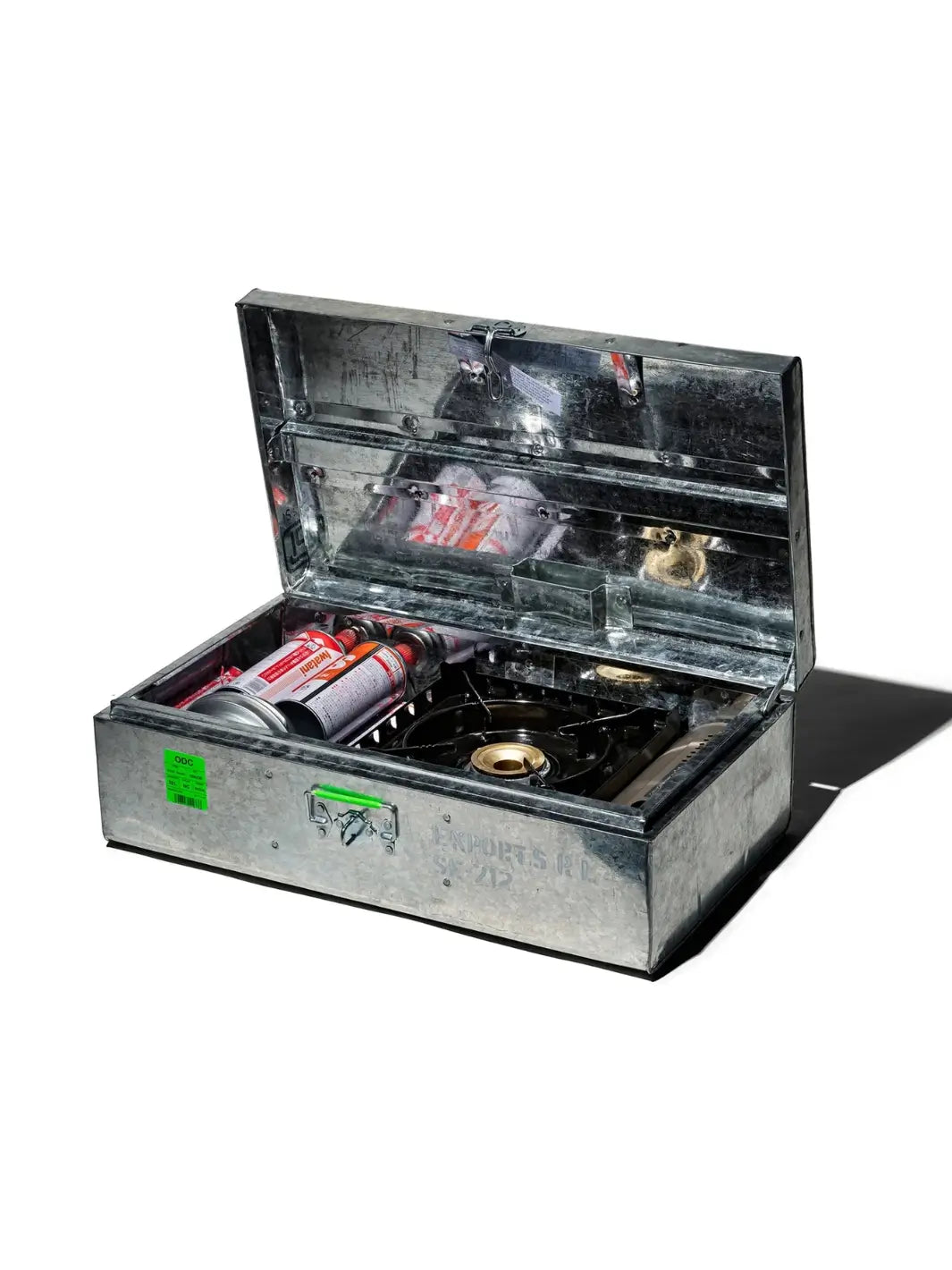 An open Steel Trunk / 22L from Puebco configured for outdoor camping use, containing a portable gas stove burner and multiple fuel canisters | Twentyseven Toronto