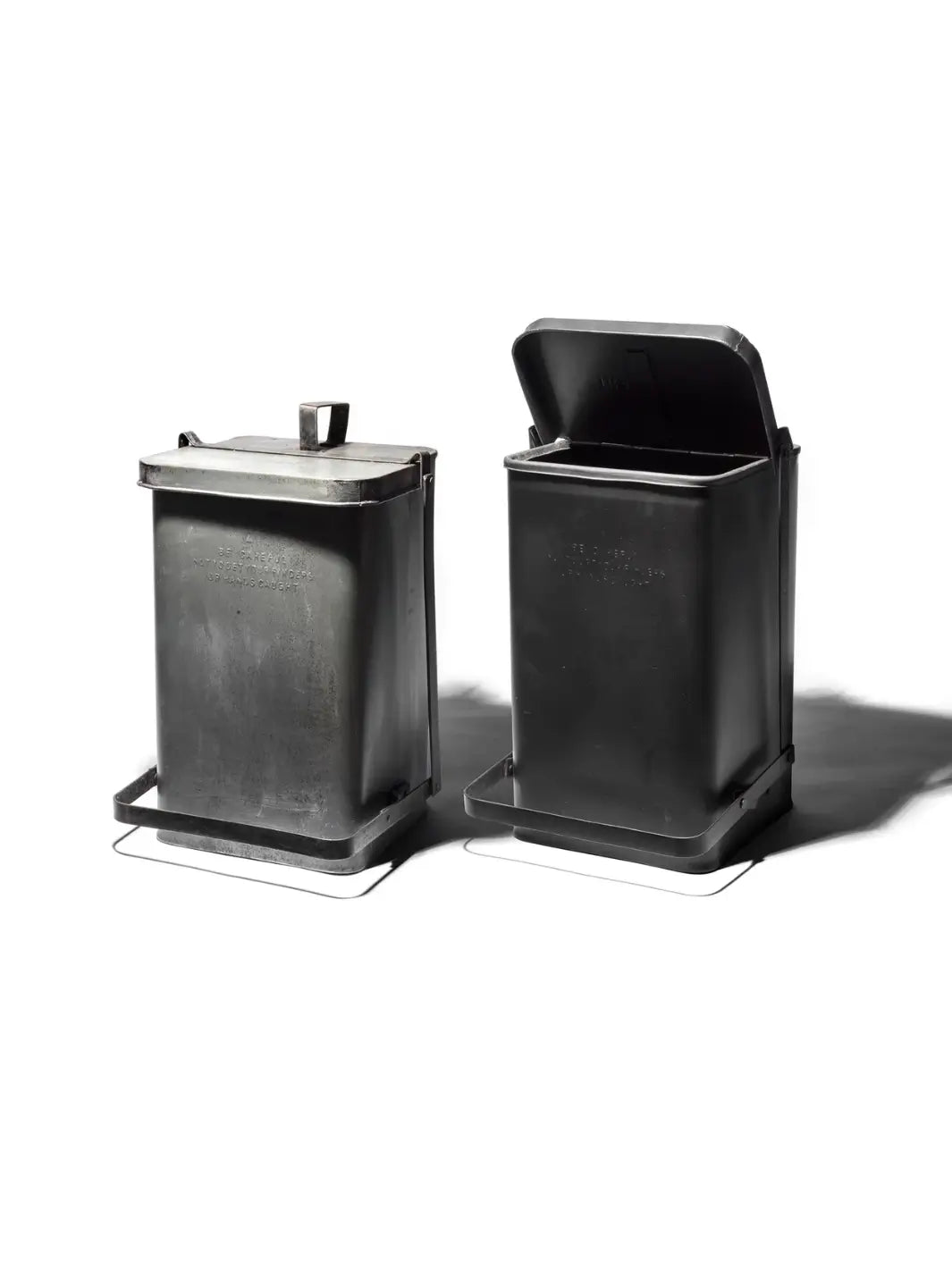 Two industrial-style Step Trash Can - Natural from Puebco are shown side-by-side against a white background, one with its lid closed and the other with its lid pressed open | Twentyseven Toronto