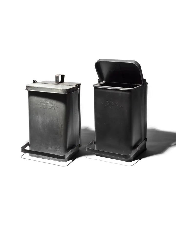 Two industrial-style Step Trash Can - Natural from Puebco are shown side-by-side against a white background, one with its lid closed and the other with its lid pressed open | Twentyseven Toronto