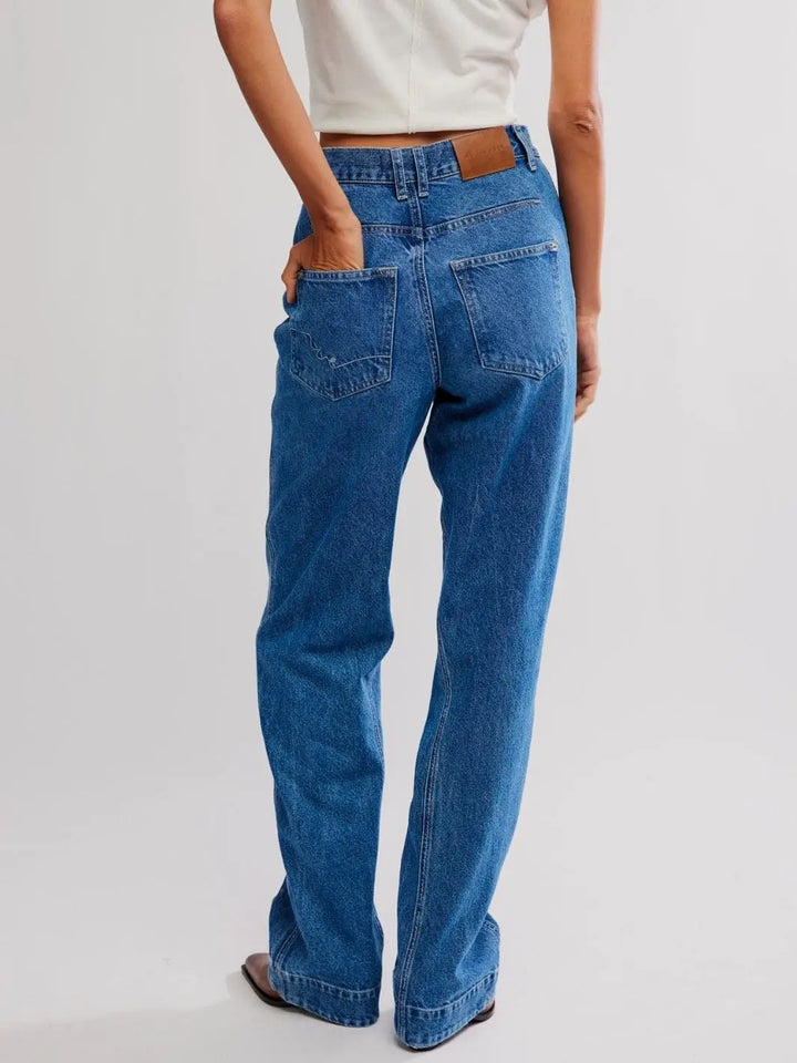 A rear view features a model with their hand in the back pocket, showing the leather brand patch on the Free People Stick Around Slim Curve Jeans - Stay For The Morning | Twentyseven Toronto