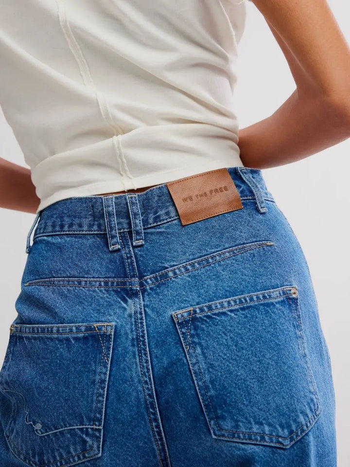 A close-up back shot focuses on the "We The Free" leather label, back pockets, and denim texture of the Free People Stick Around Slim Curve Jeans - Stay For The Morning | Twentyseven Toronto