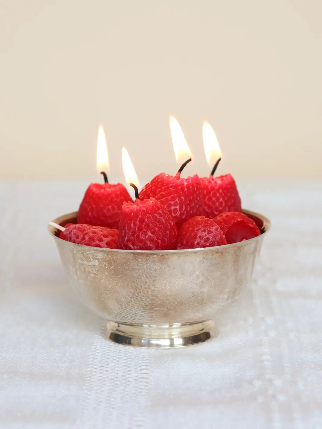 Bowl with lit strawberry beeswax candles on a white surface | Twentyseven Toronto