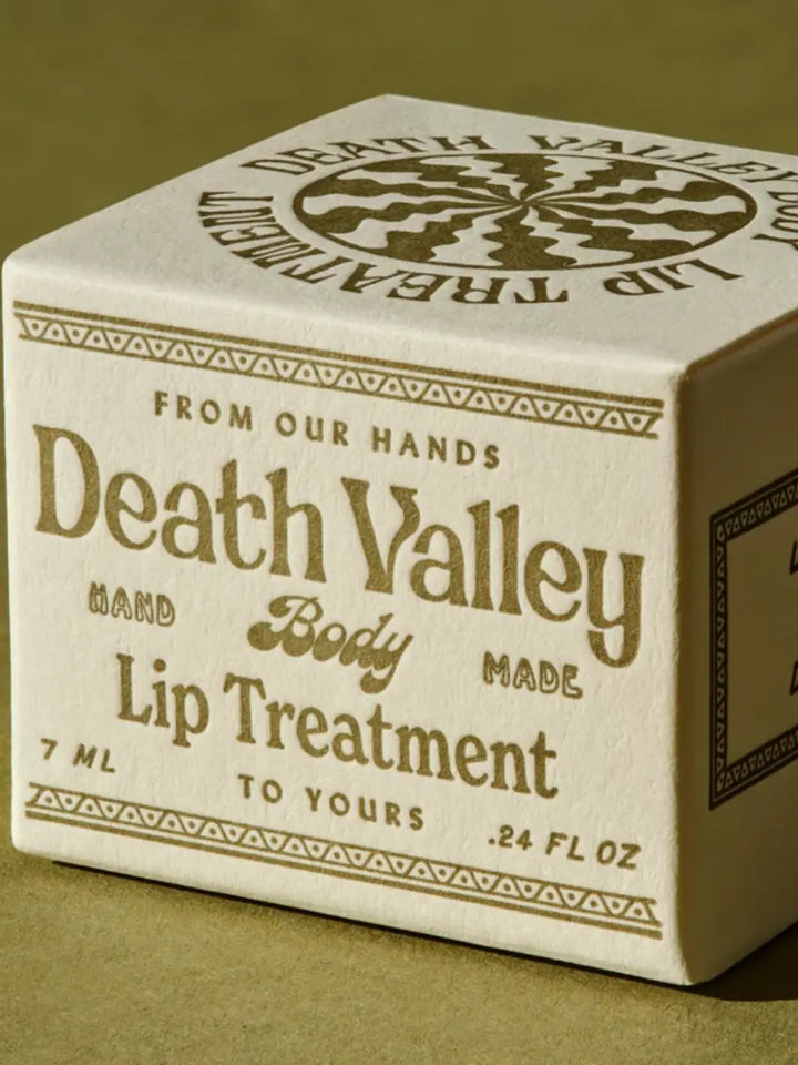 A close-up studio shot highlights the front text and vintage typography on the cardboard box for Death Valley Nails Strawberry + Lime + Coconut Lip Treatment | Twentyseven Toronto
