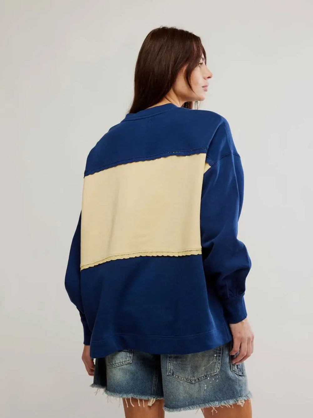 A back view captures a model showcasing the large cream color-blocked panel and delicate lace-trimmed hem on the Free People Strawberry Sweatshirt - Oceana Combo | Twentyseven Toronto