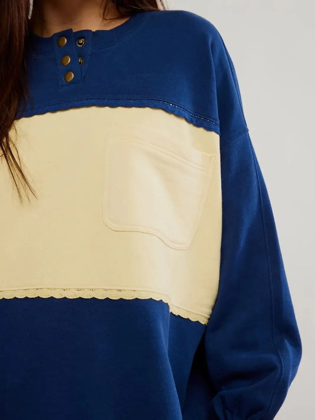 A close-up shot highlights the front patch pocket, contrasting cream chest panel, and bronze snap buttons of the Free People Strawberry Sweatshirt - Oceana Combo | Twentyseven Toronto