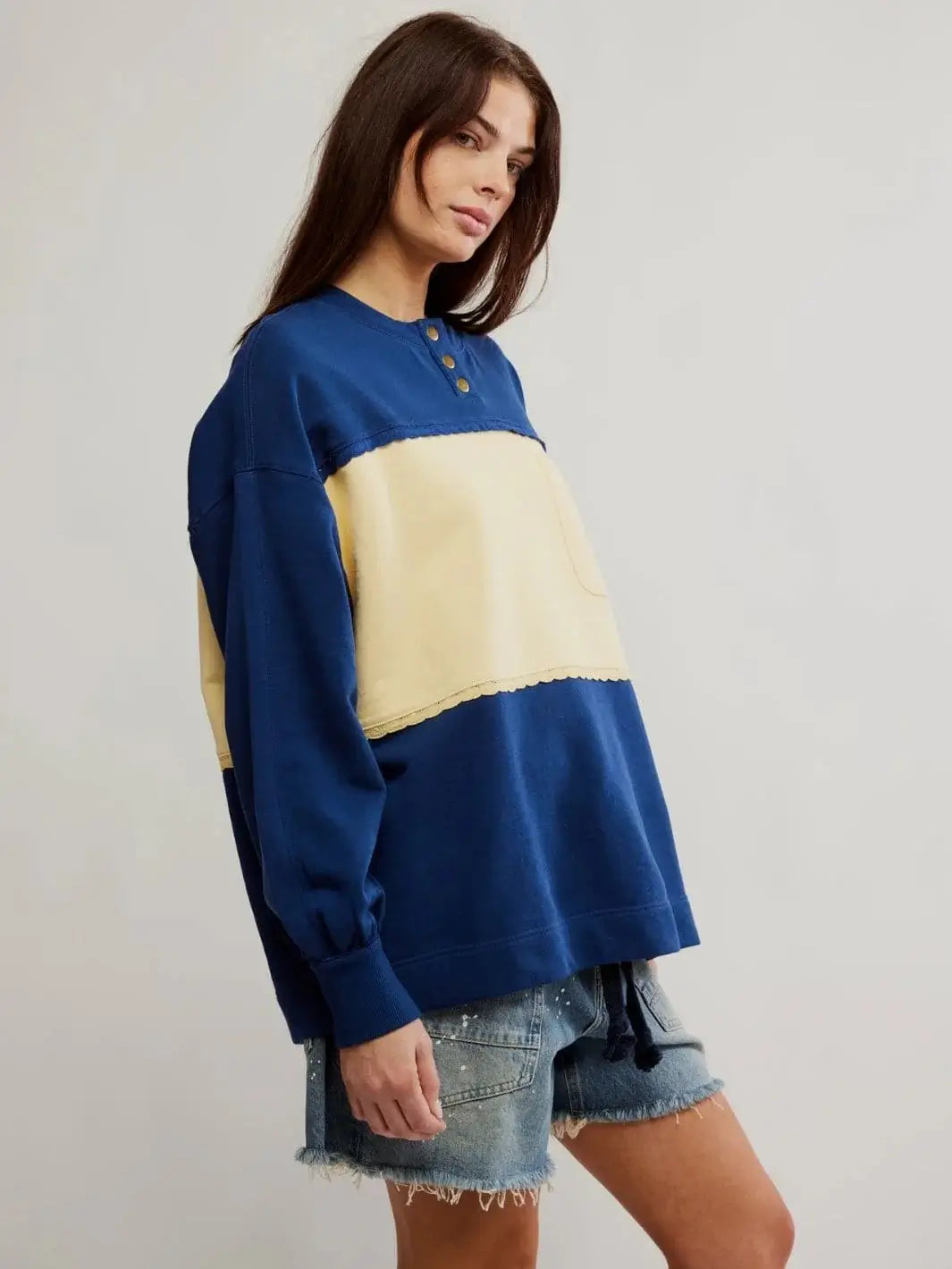 A side profile view displays the slouchy fit, dropped shoulders, and ribbed cuffs of the blue color-blocked Free People Strawberry Sweatshirt - Oceana Combo | Twentyseven Toronto